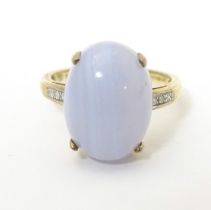 A 9ct gold dress ring set with lace agate cabochon flanked by three diamonds to each shoulder.