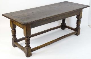 A mid 17thC joined oak refectory table with a three plank top above cup and cover turned legs united