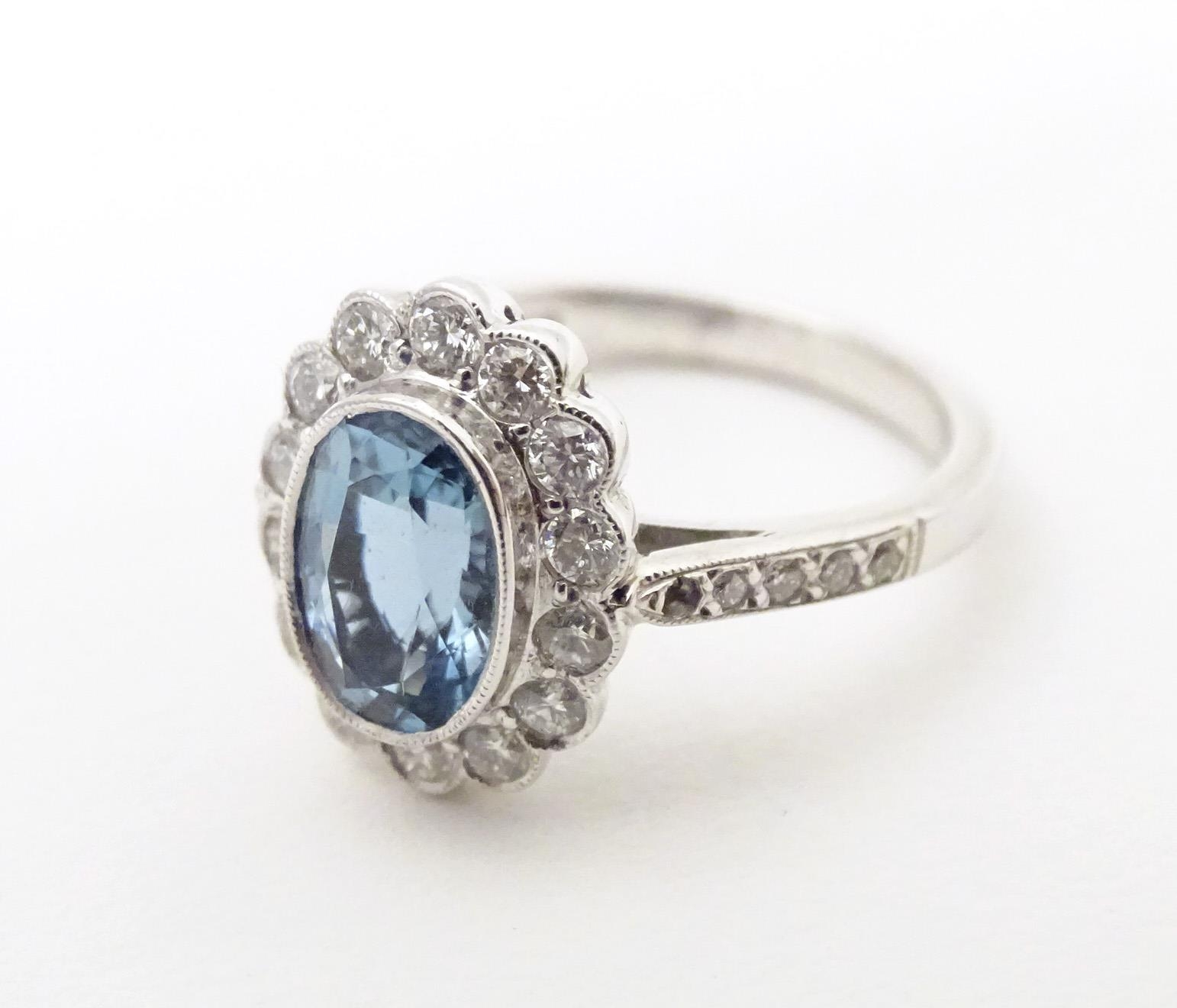 A 9ct white gold ring set with aquamarine coloured oval stone to centre bordered by diamonds with