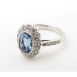 A 9ct white gold ring set with aquamarine coloured oval stone to centre bordered by diamonds with