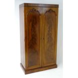 A mid 19thC mahogany double wardrobe with two panelled doors adorned with carved foliage and opening