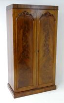 A mid 19thC mahogany double wardrobe with two panelled doors adorned with carved foliage and opening