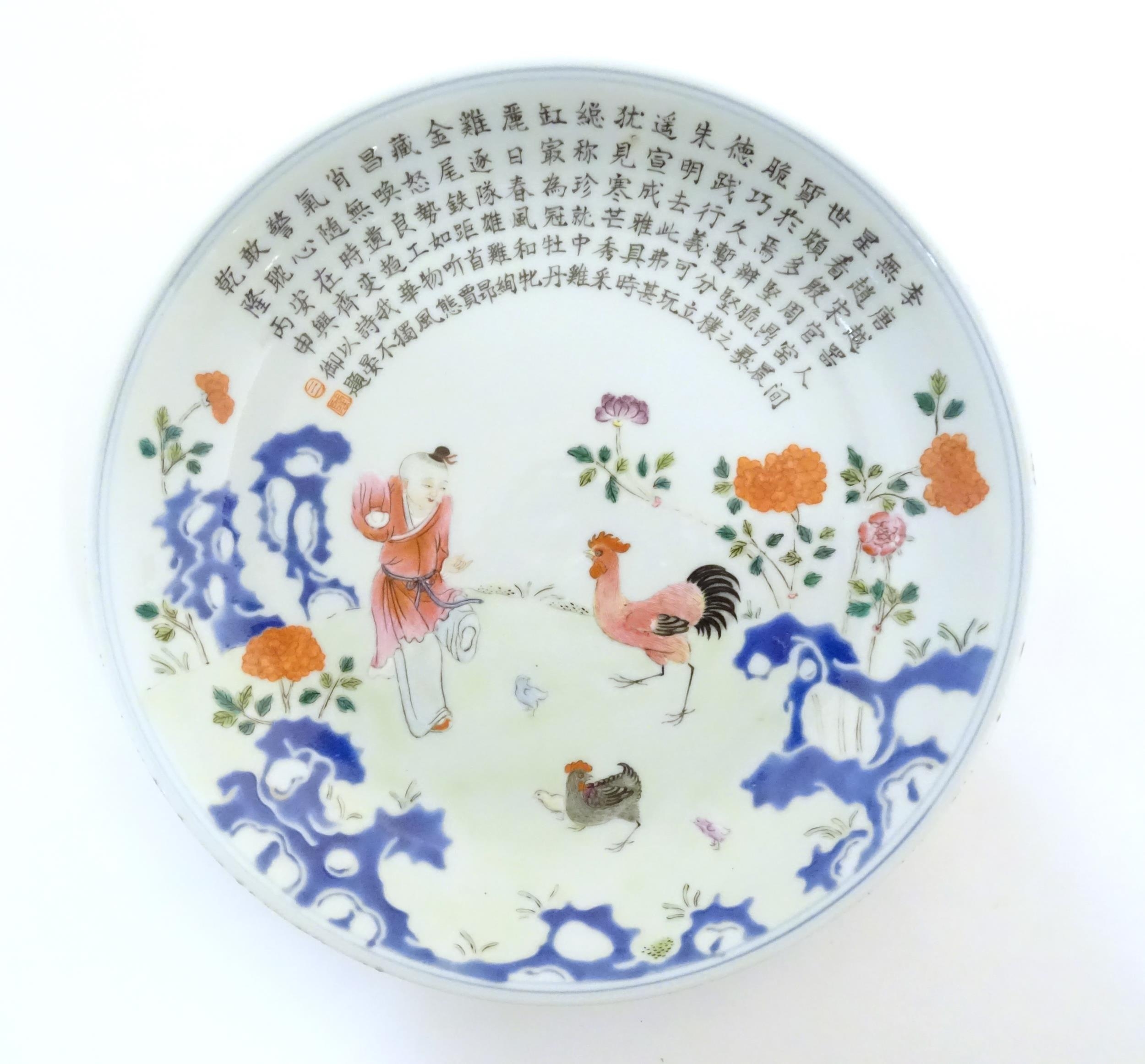 A Chinese famille rose plate decorated with a figure, a cockerel, hen and chicks in a garden with