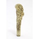 A 19thC Oriental carved bone cane handle modelled as a bird in a tree with leaves and fruit /