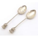 A pair of Scottish silver teaspoons the handles surmounted by thistle detail, hallmarked Glasgow