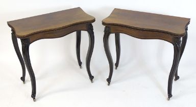 A pair of 19thC rosewood card tables of serpentine form, having beaded edges above floral carved