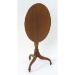 A 19thC mahogany tripod table with oval top above a turned pedestal base and three legs