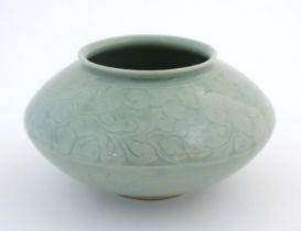 A Chinese celadon style vase of squat form with relief foliate decoration. Character marks to