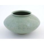 A Chinese celadon style vase of squat form with relief foliate decoration. Character marks to