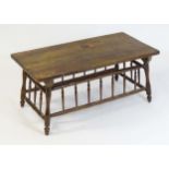 An Arts and Crafts style low table with an elm top above four turned tapering splayed legs united by