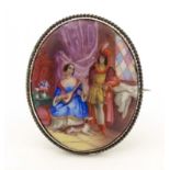An oval brooch with enamel scene to centre depicting a couple with their dog, within a white metal