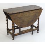 A c.1700 oak drop leaf table with oval leaves above turned supports united by a box stretcher. 38"