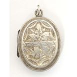 A white metal pendant locket of oval form with foliate decoration 1 1/4" high Please Note - we do