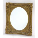 A 19thC giltwood and gesso mirror with a decorative moulded frame and an oval aperture to the