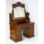 An Aesthetic period walnut dressing table / dressing chest. Having a pointed pediment above carved