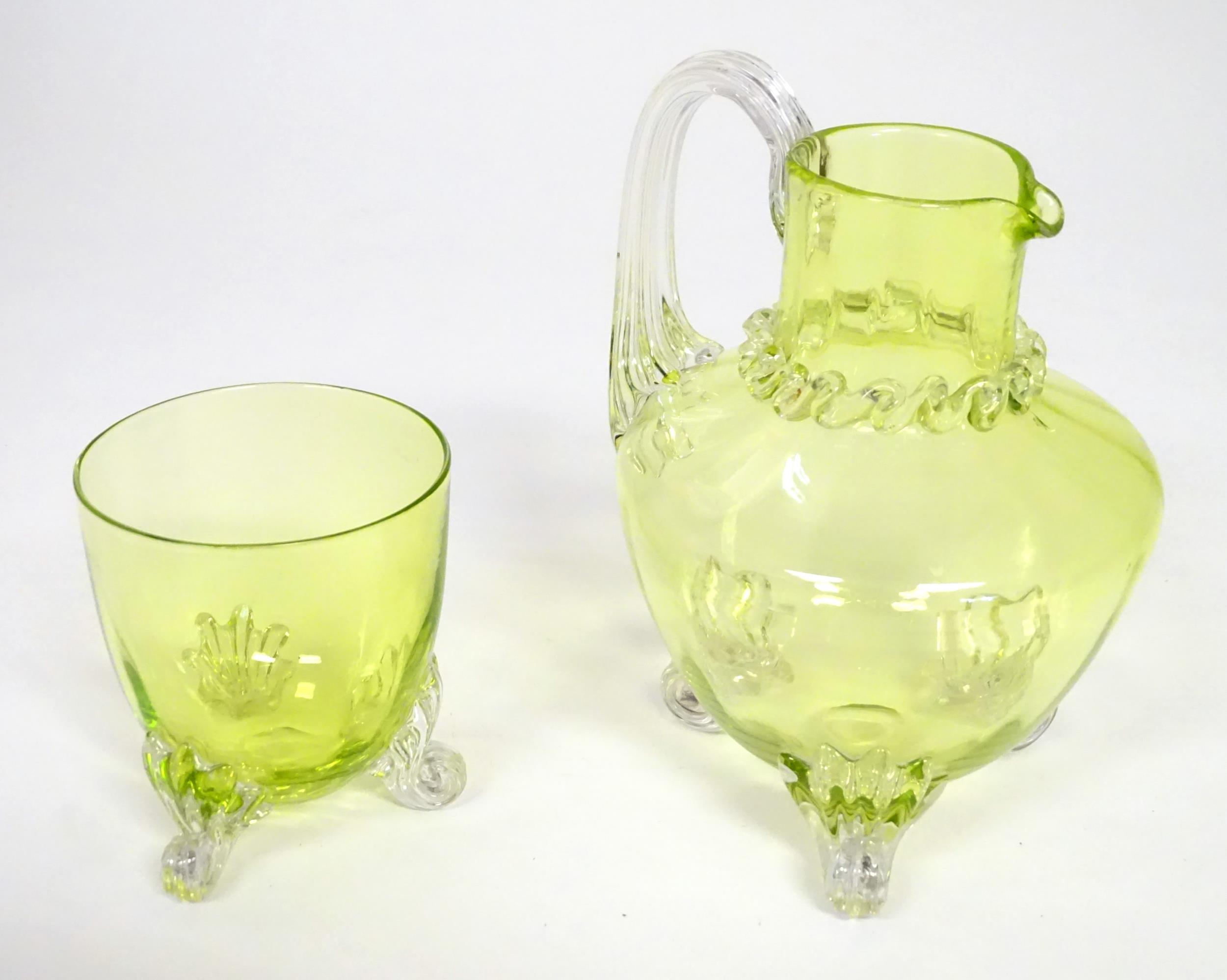 A yellow glass water jug with clear glass handle and feet, together with a matching glass. The jug 6