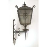 An early 20thC exterior lamp and wall bracket, of lantern form and constructed of wrought iron, with