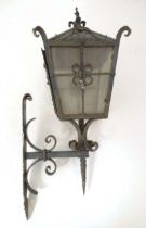 An early 20thC exterior lamp and wall bracket, of lantern form and constructed of wrought iron, with