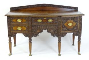 A late 19thC Anglo-Indian sideboard with a profusely detailed carved carcass and drawer fronts, a