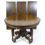 A 19thC oak extending dining table, having a circular top with a carved rim and a large heavily
