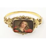 A 19thC gold bangle formed bracelet set with central hand painted ceramic cabochon depicting