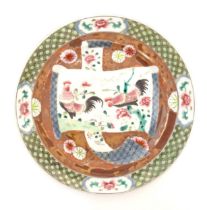 A Chinese plate decorated with a scrolling central panel depicting two cockerels / roosters