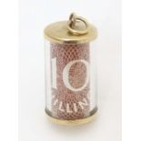 A 9ct gold novelty pendant / charm of cylindrical form with rolled 10 shilling note to centre.