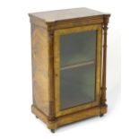 A Victorian burr walnut pier cabinet with a castellated top above a glazed door flanked by turned
