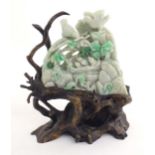 A Chinese light jade coloured hardstone 'boulder' carving depicting birds feeding chicks in a nest