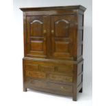 An early / mid 18thC oak livery cabinet with a moulded cornice above panelled sides and two panelled