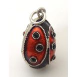 A white metal pendant charm of egg form with stylised ladybird / ladybug detail with enamel