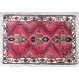 Carpet / Rug : A red ground rug with cream ground border decorated with floral and geometric motifs.
