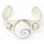 A .925 silver bracelet of cuff bangle form with shiva shell decoration. Please Note - we do not make
