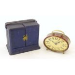 A 20thC French red lacquered travelling alarm clock with chinoiserie decoration. The dial signed