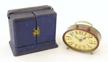 A 20thC French red lacquered travelling alarm clock with chinoiserie decoration. The dial signed