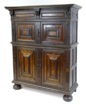 A 17thC oak livery cupboard with a moulded cornice above carved mask decoration and pierced