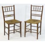 A pair of Arts & Crafts Sussex chairs with turned backrests and uprights above an envelope rush seat