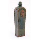 A Continental terracotta gin / spirit bottle / flask of tapering form with a green glaze, incised