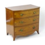 A late Georgian mahogany chest of drawers with a bow front above three long drawers with brass