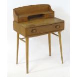 A mid / late 20thC elm Ercol school desk with a shaped upstand above two small drawers and one
