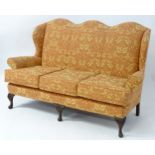 A mid 20thC camel back settee /sofa with scrolled arms and standing on carved cabriole legs. 69"