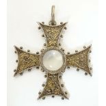 A white metal pendant of cross form with scroll detail, set with central moonstone cabochon. Approx.