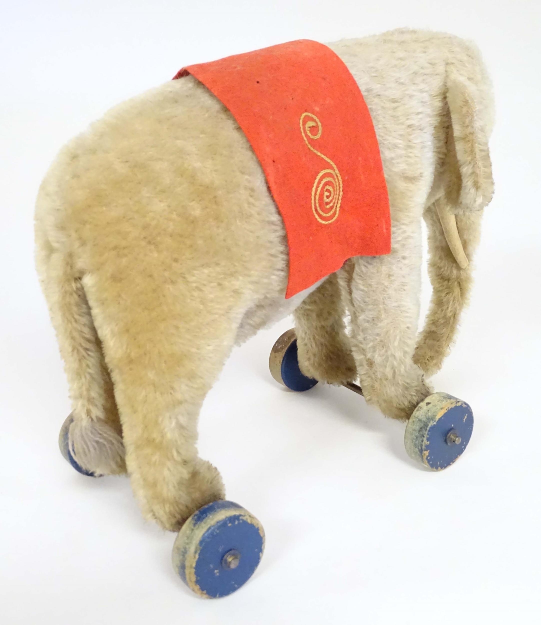 Toy: An early 20thC Steiff mohair pull along elephant toy with felt saddle, upon four wooden wheels, - Image 5 of 9