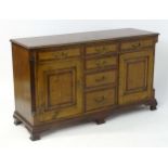 A George III style oak sideboard with a moulded top above six short drawers and two panelled