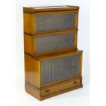 An early 20thC Globe Wernicke barrister / elastic bookcase, having three tiers with leaded glass and