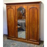 A 19thC mahogany triple wardrobe with a moulded cornice above three arched doors with a carved