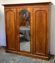 A 19thC mahogany triple wardrobe with a moulded cornice above three arched doors with a carved