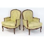 A pair of late 20thC fauteuil armchairs with floral carved frames. 29" wide x 27" deep x 40" high.