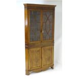 An early 19thC mahogany corner cupboard, having a moulded cornice above two astragal glazed doors