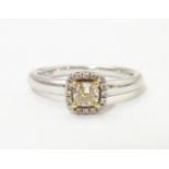 An 18ct white gold ring set with central canary diamond bordered by white diamonds. Ring size